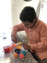 High angle view of boy painting easter eggs on table at home