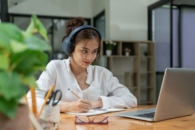 Young woman using mobile phone while sitting at cafe