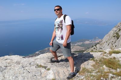 Full length of young man wearing sunglasses on rock