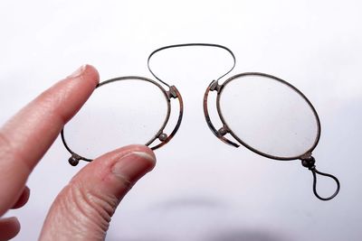 Close-up of hand holding eyeglasses against white background