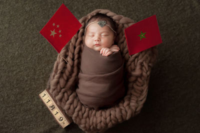 High angle view of cute baby boy wrapped in blanket sleeping in basket