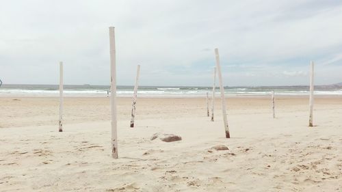 Wooden posts at beach against sky