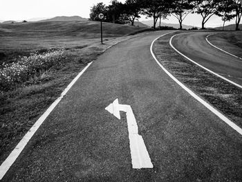 Arrow symbol on road amidst field