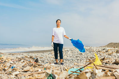 Young volunteer on beach full of garbage