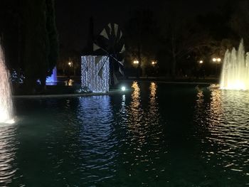 Illuminated buildings by river at night