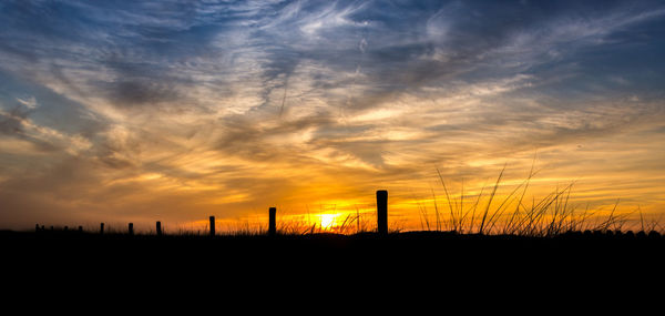 Silhouette field against sky during sunset