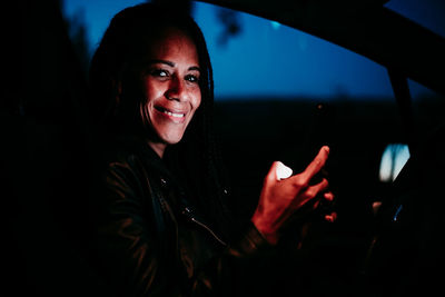 Portrait of smiling woman using mobile phone while sitting in car