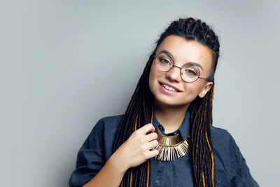 Portrait of young woman standing against gray background