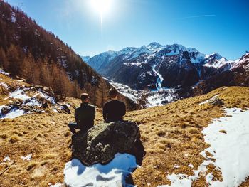 Rear view of people on snowcapped mountain against sky