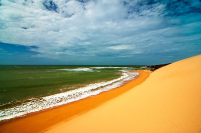 Scenic view of beach against cloudy sky