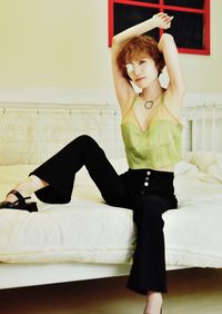 Full length portrait of happy woman relaxing on bed at home