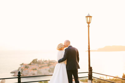 Rear view of couple kissing against sky