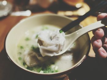 Cropped hand of person having wonton soup at table