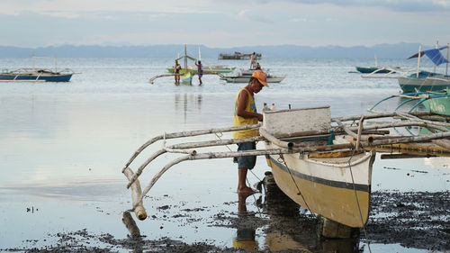 Man fishing on beach against sky