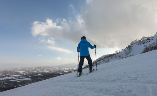 Low angle view of man skiing on snowcapped mountain against sky