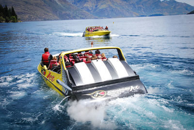 People in boat on sea against mountain