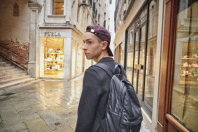 Young woman looking away while standing against building in city