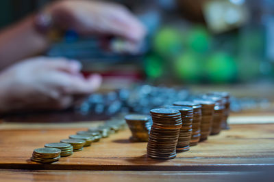 Cropped hand of woman counting coins while stacking on table