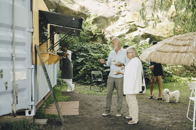 Senior man and woman talking while having food outside truck in park