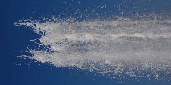 Close-up of water splashing against blue sky