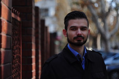 Portrait of young man standing by brick wall