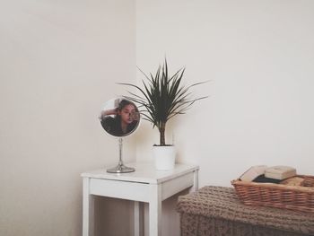 Reflection of woman in mirror on table at home