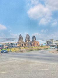 Road by buildings against sky