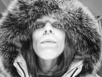 Close-up portrait of young woman wearing fur coat at home