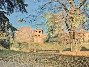 Old building by trees on field against sky