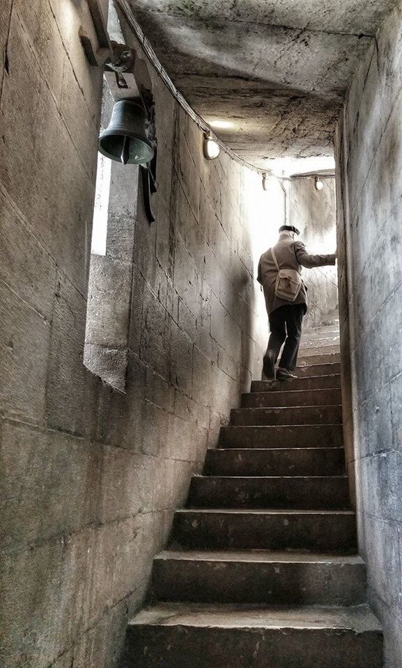 LOW ANGLE VIEW OF MAN MOVING UP ON STAIRCASE IN BUILDING