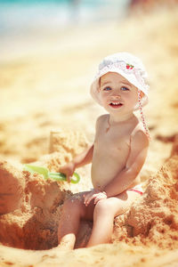 Portrait of cute girl sitting on sand at beach