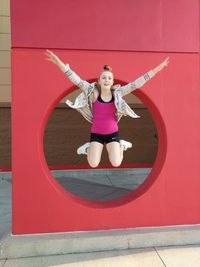 Portrait of smiling young woman against red wall