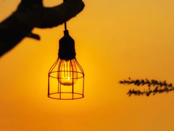 Close-up of illuminated lamp against orange sky