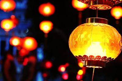 Close-up of illuminated light bulb hanging at night