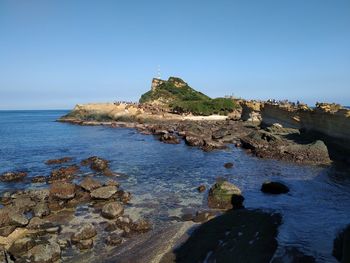 Rocks on beach against clear blue sky