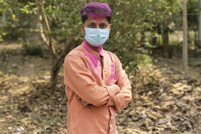 An indian man in surgical nose mask and colorful face with powder paint during holi in pandemic