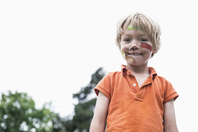 Portrait of injured boy standing against clear sky