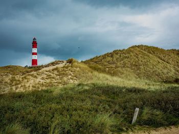 Lighthouse on field against sky