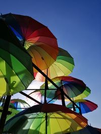 Low angle view of multi colored umbrella against clear blue sky