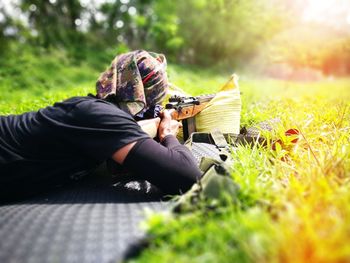 Man shooting rifle while lying on grass outdoors