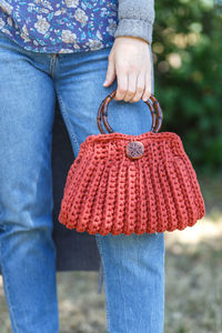 Midsection of woman holding red purse