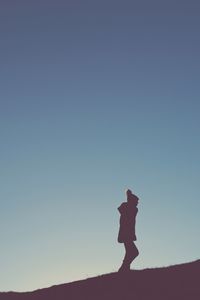 Silhouette woman standing in desert against clear blue sky