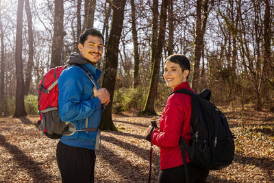 The smiling young couple is walking in the woods. 