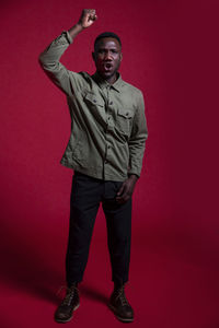 Portrait of young man standing against red background