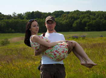 Portrait of man carrying woman on grassy field