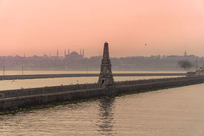 View of river and buildings against sky during sunset