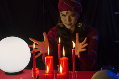 Female fortune teller with burning candles at home