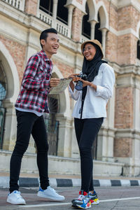 Full length of young woman standing on phone in city