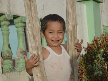 Portrait of cute baby boy standing by railing