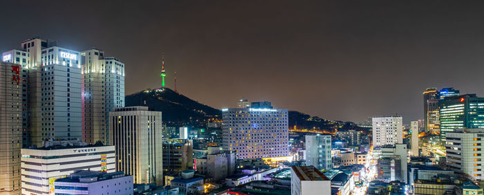 Illuminated buildings in city against sky at night